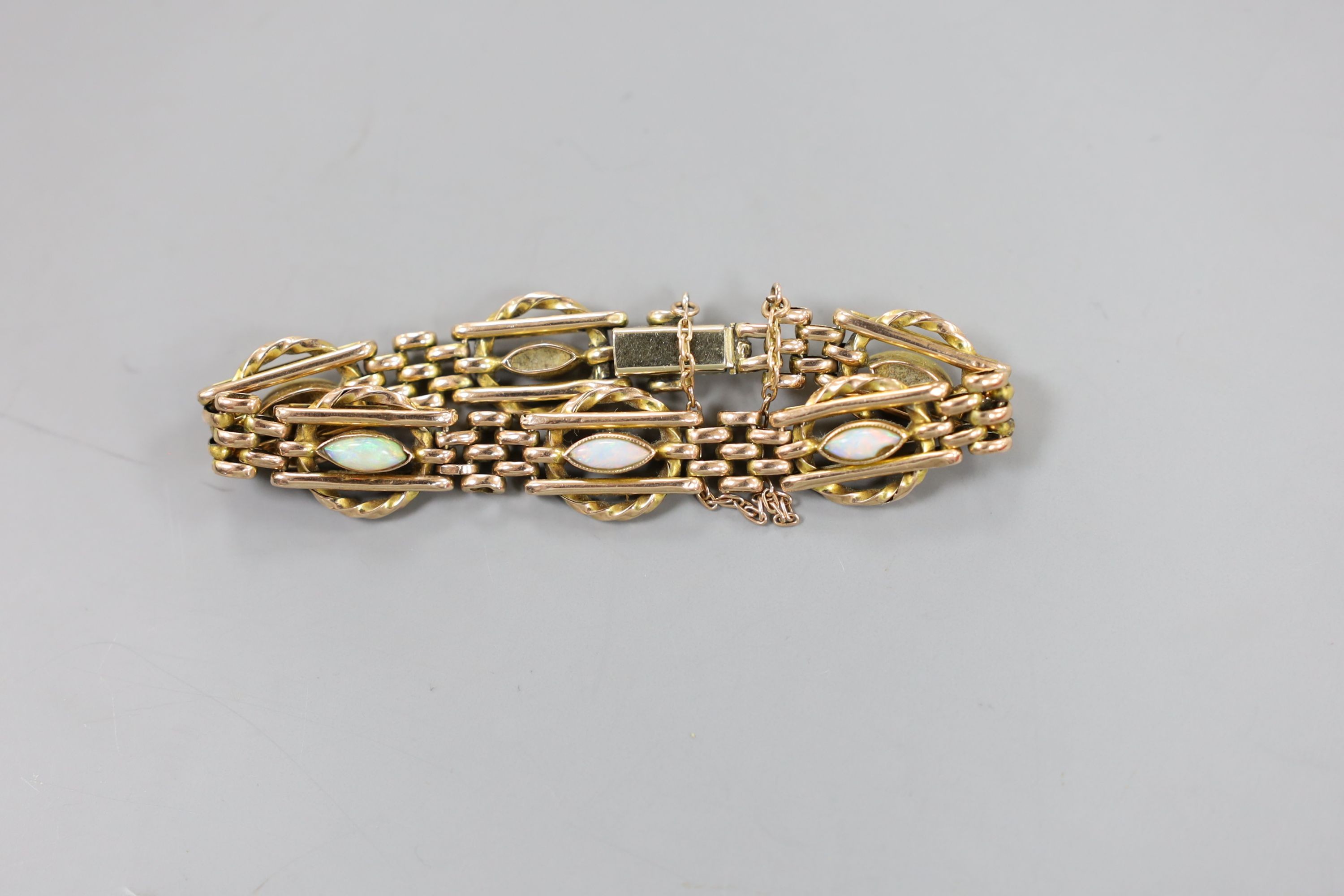 An Edwardian yellow metal and six stone navette shaped white opal set bracelet, with safety chain, 15cm, gross weight 10.6 grams.